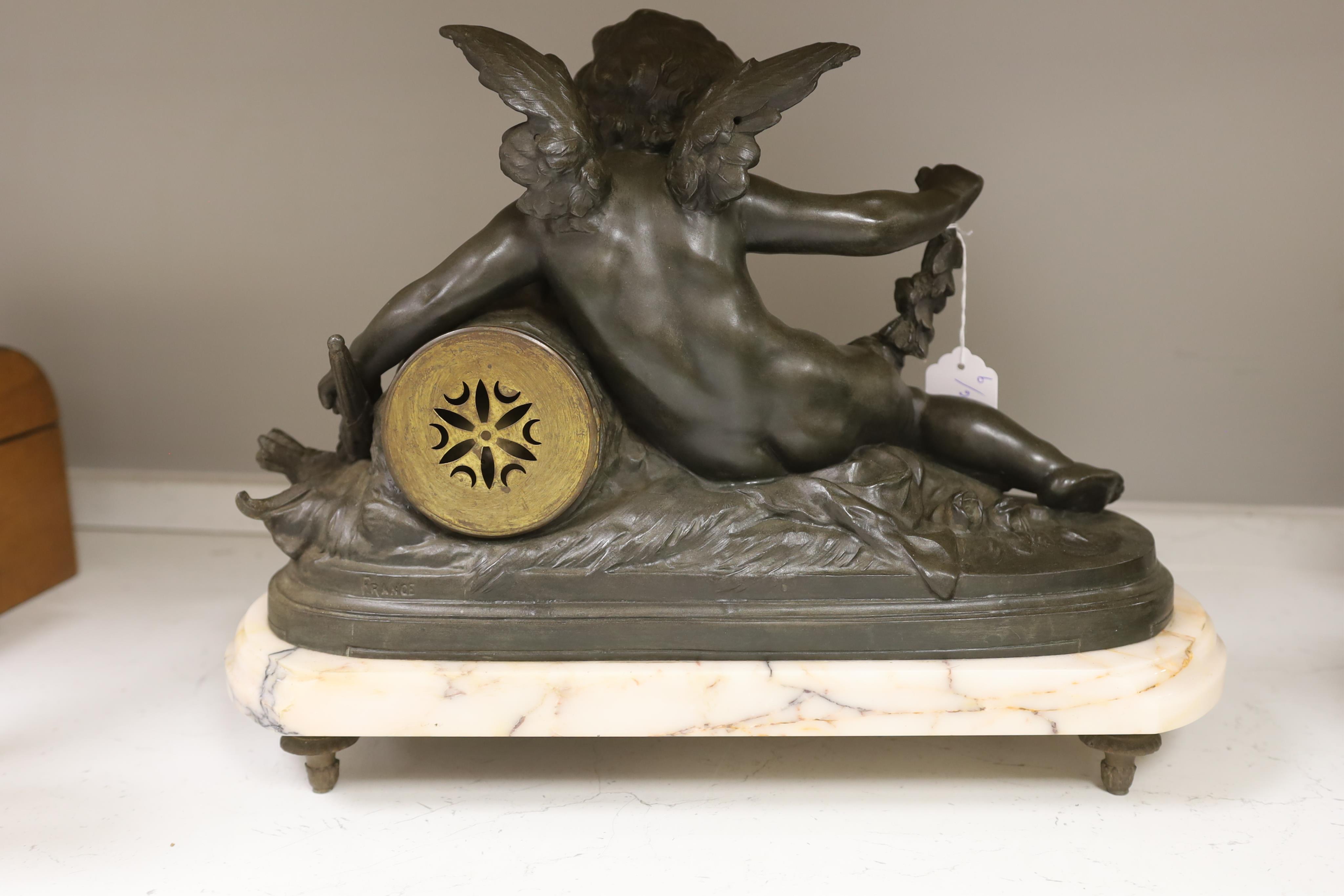 After Francois Hippolyte Moreau (French, 1832-1926), a late 19th century bronze cherubic mantel clock on marble base, ‘Amour Brûlant Ses Armes’, no key or pendulum, 34cm high. Condition - clock glass missing, not known i